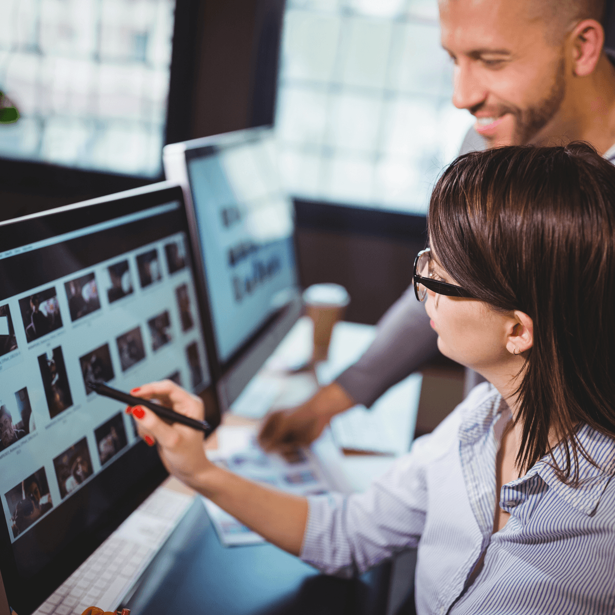 Zwei Marketing Manager sitzen vor einem Bildschirm und wählen Fotos eine Display-Kamagne aus