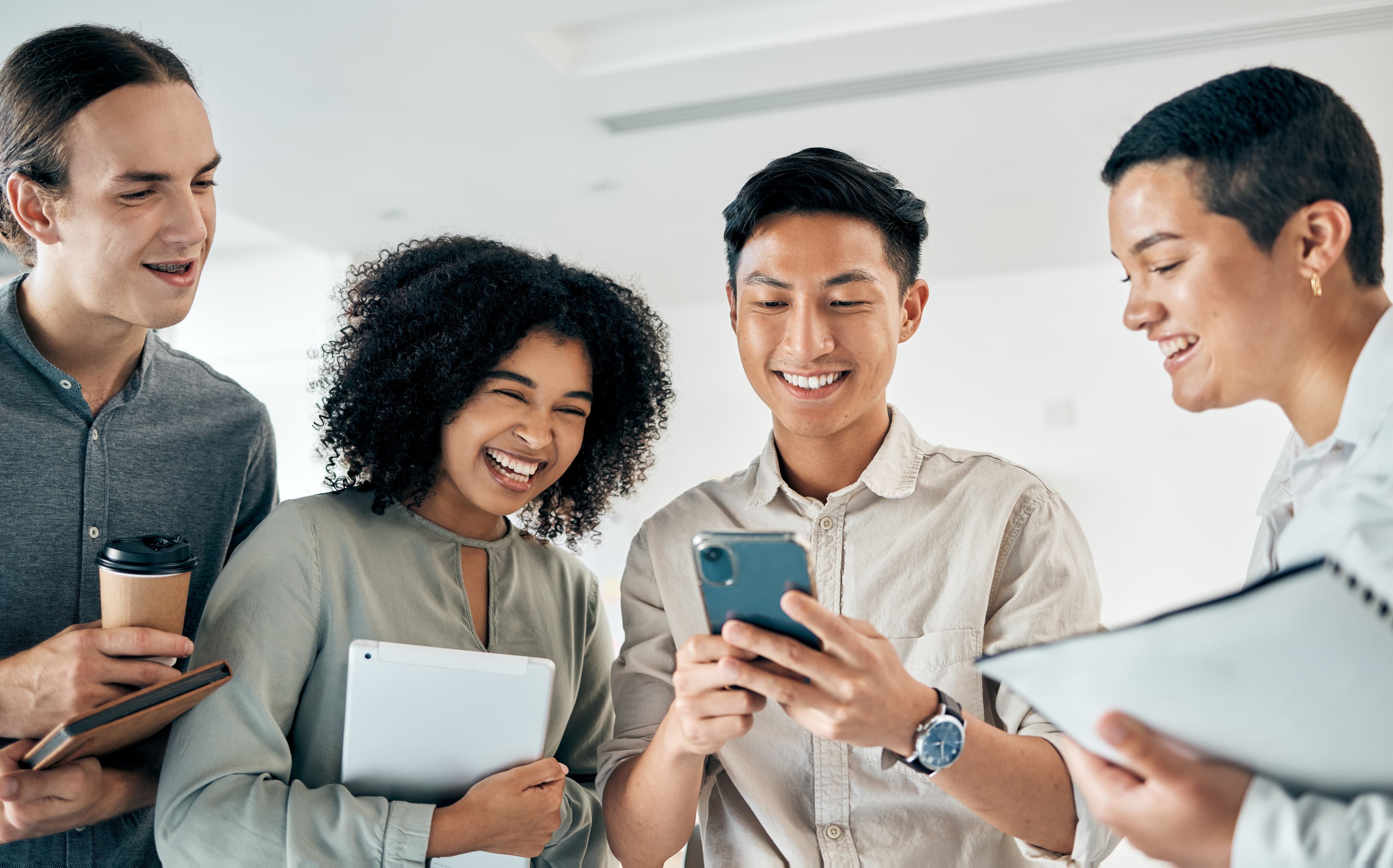 Vier Personen schauen sich auf einem Handy die neue Kampagne zum Social Media Recruiting an