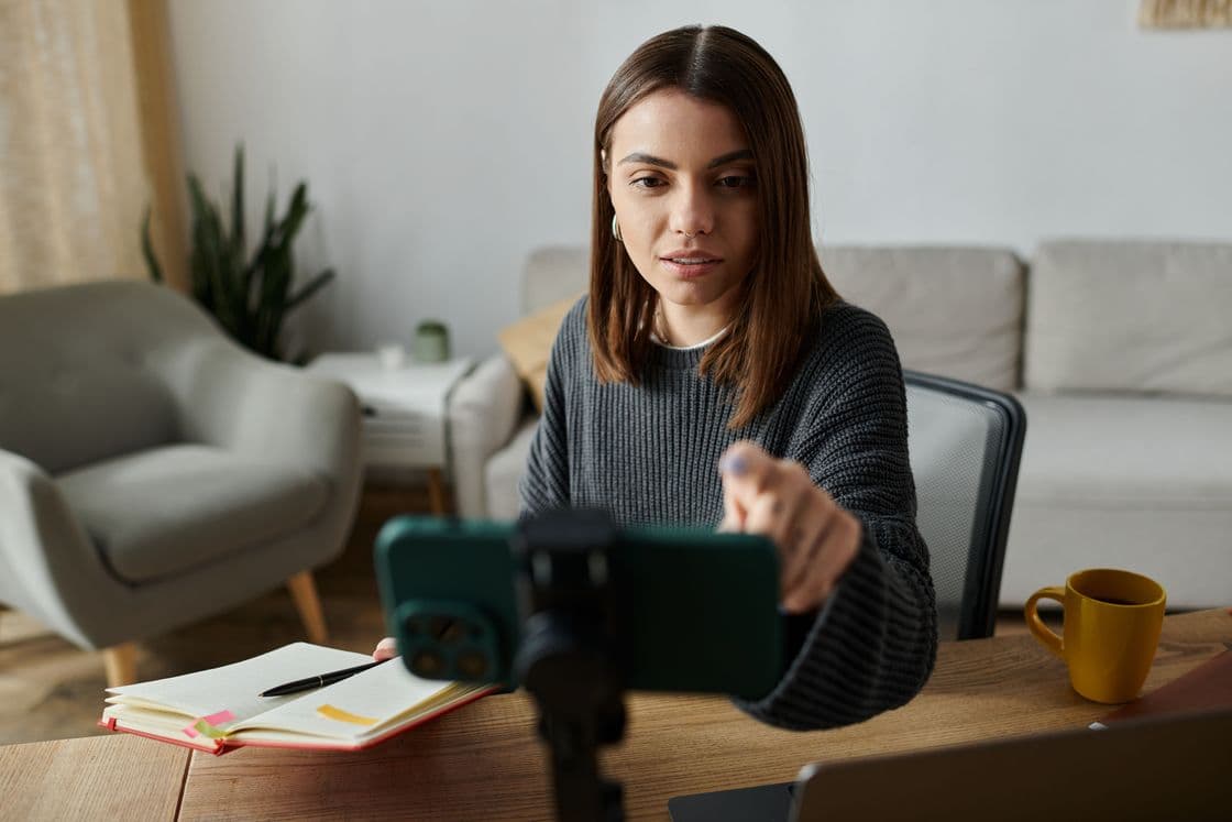 Content Managerin sitzt am Schreibtisch, Notizbuch neben ihr, Smartphone vor ihr auf dem Tisch